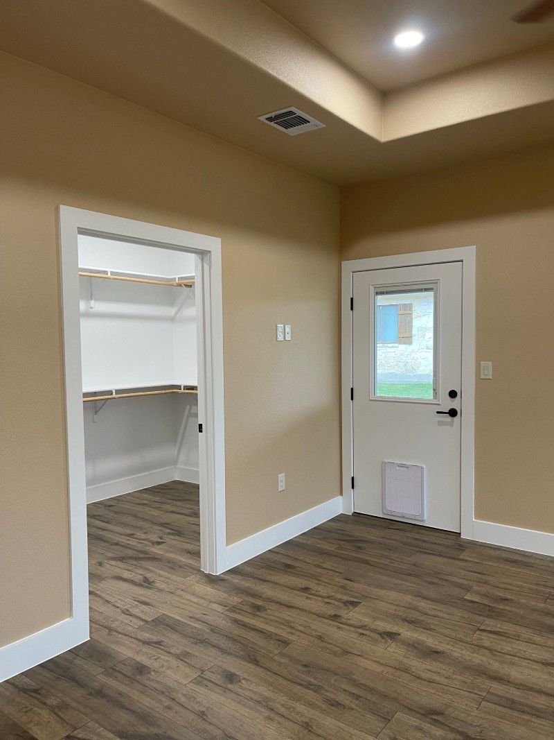 An empty room with hardwood floors and a door leading to a walk in closet.