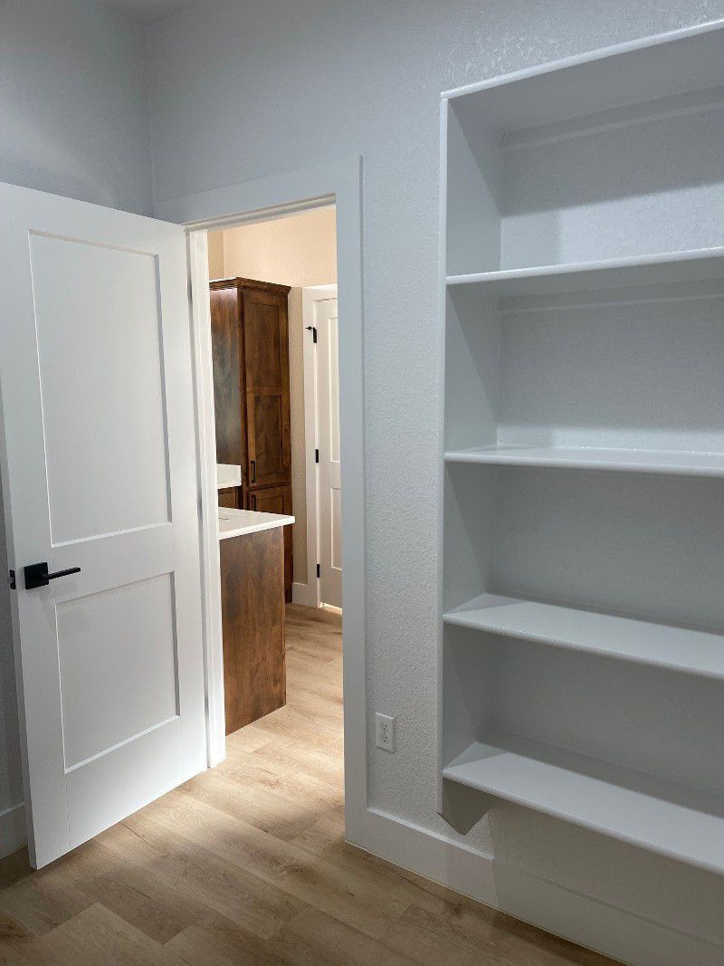 A room with white shelves and a door leading to a bathroom.