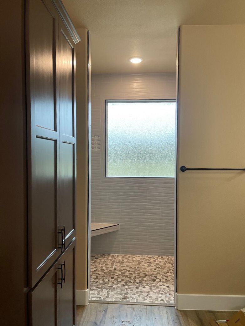 A bathroom with a walk in shower and a window.
