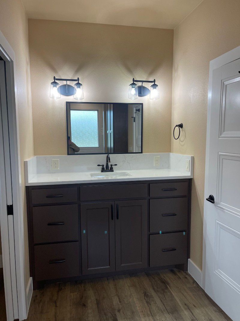 A bathroom with a sink , mirror and drawers.