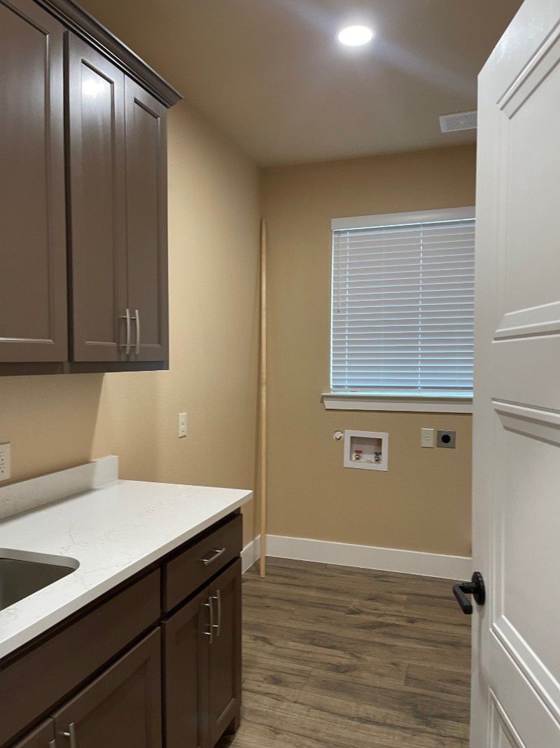 A kitchen with brown cabinets , a sink , and a window.