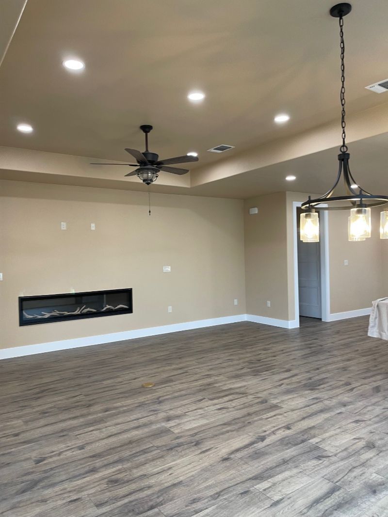 An empty living room with a fireplace and ceiling fan.