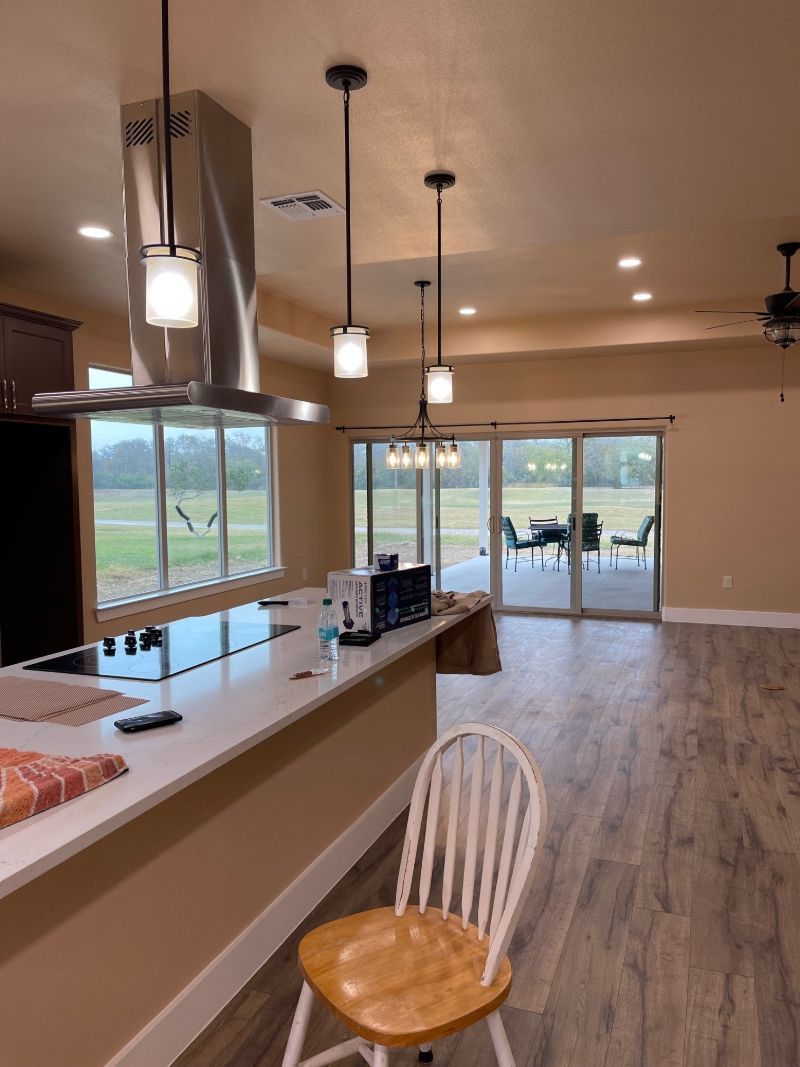 A kitchen with a wooden chair and a stainless steel hood.