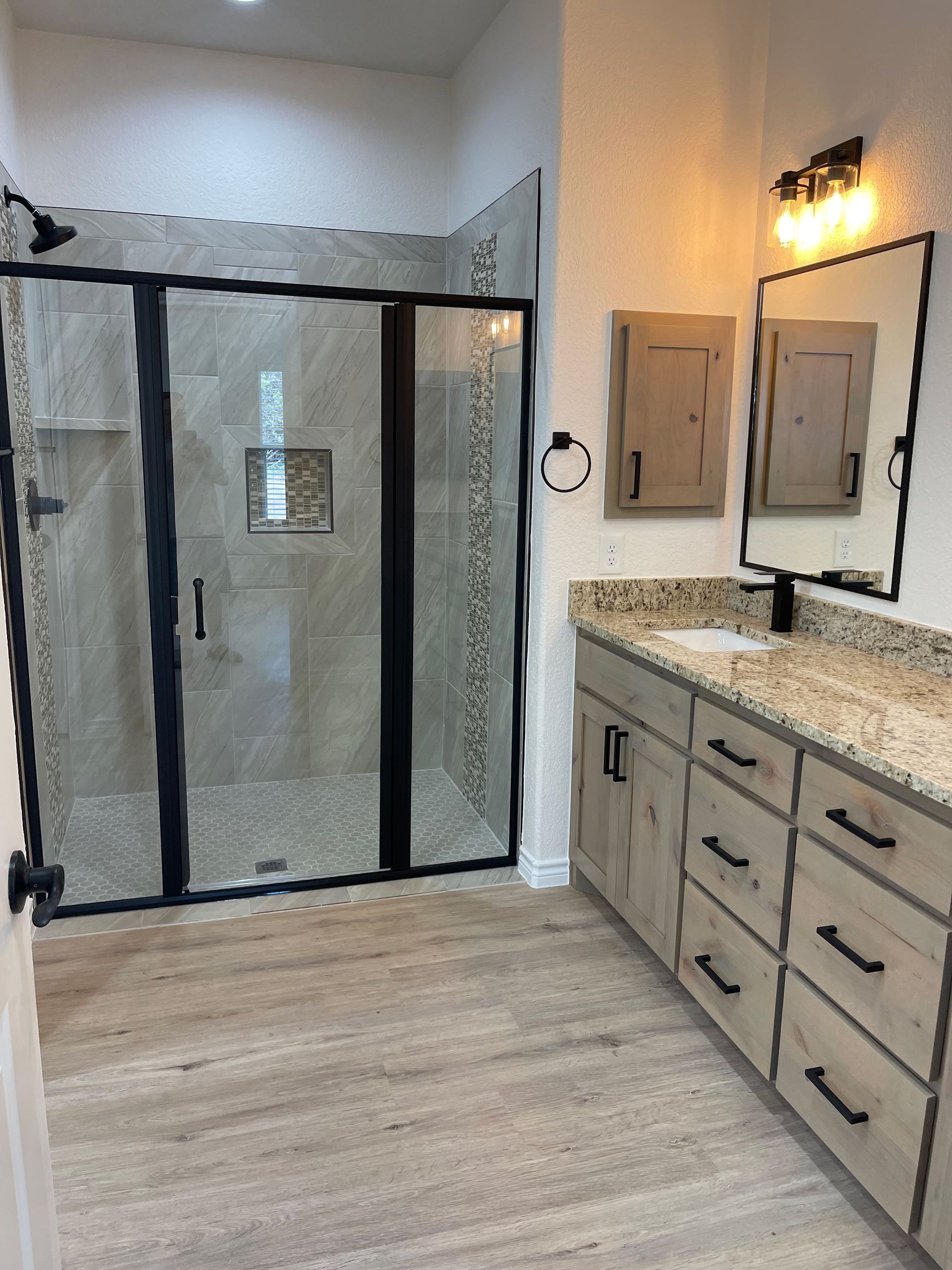A bathroom with a walk in shower , sink and mirror.