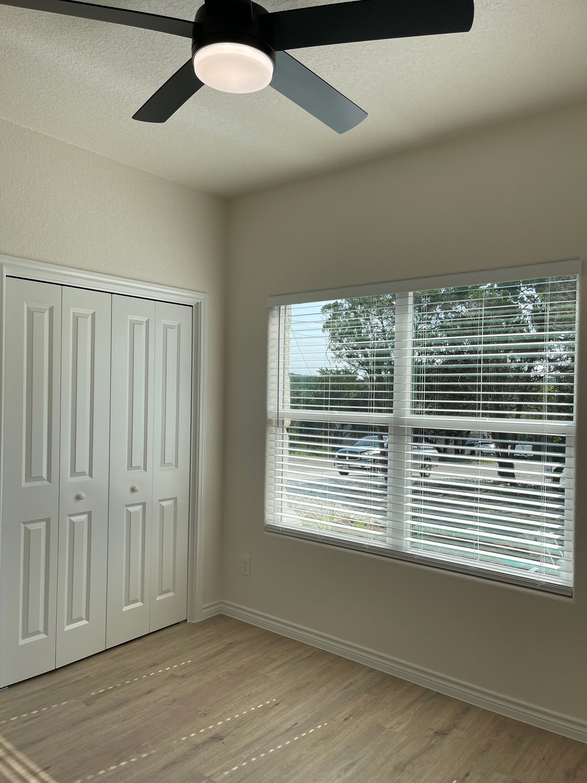 An empty room with a ceiling fan and a window