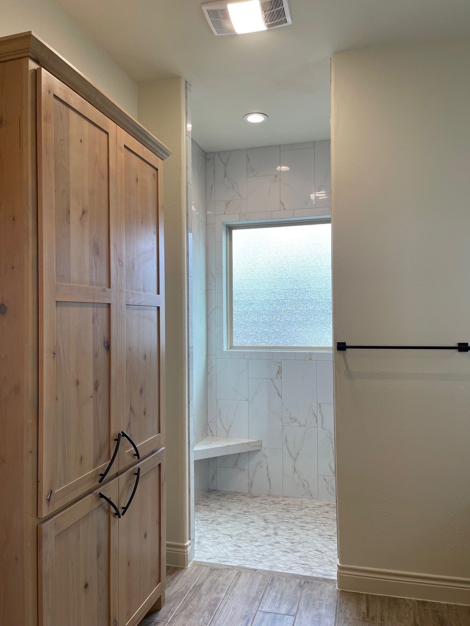 A bathroom with wooden cabinets and a walk in shower.