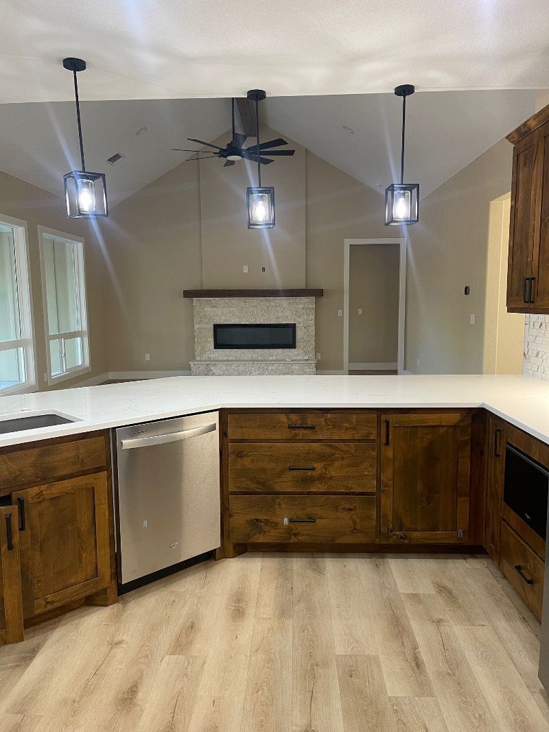 A kitchen with wooden cabinets , white counter tops , stainless steel appliances and a fireplace.