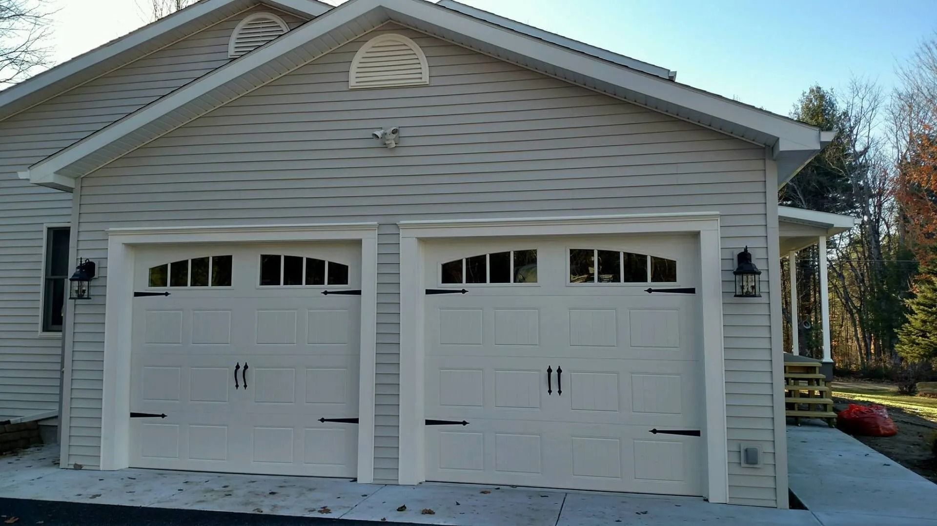 White two-car garage with arched doors on a house exterior in daylight