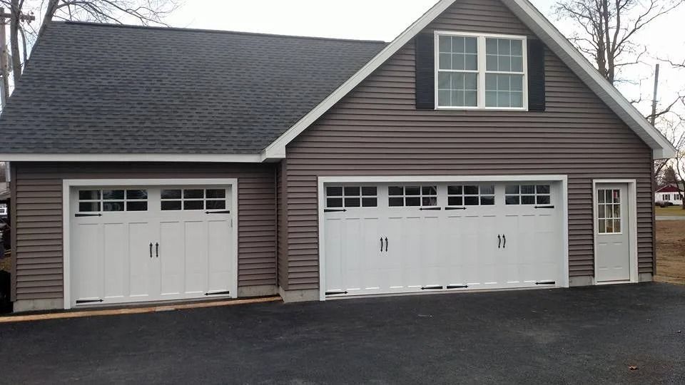 Suburban garage with two white doors and gray siding on a paved driveway