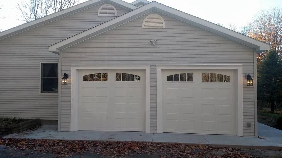 Suburban house with beige siding and two garage doors, front exterior at dusk