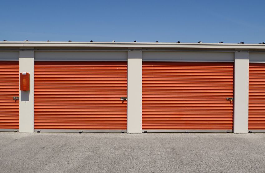 Row of orange storage unit doors with white columns under a blue sky