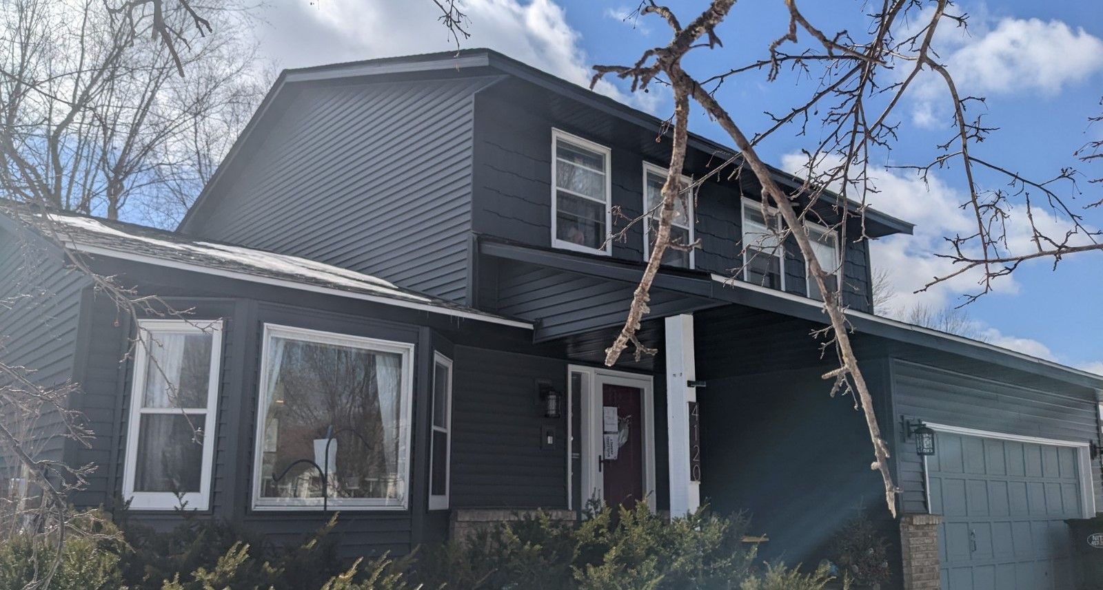 A gray deck with a black railing and stairs on the side of a house.