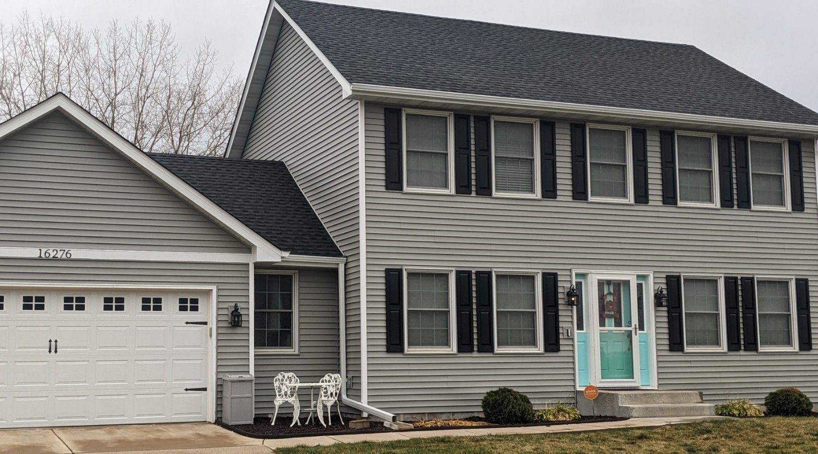 A large house with black shutters and a white garage door.