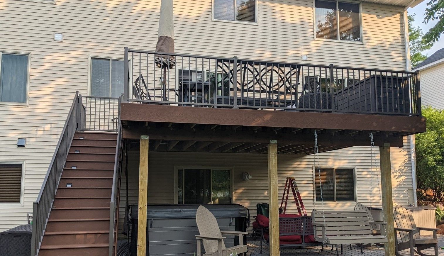 The back of a house with a large deck and stairs leading up to it.