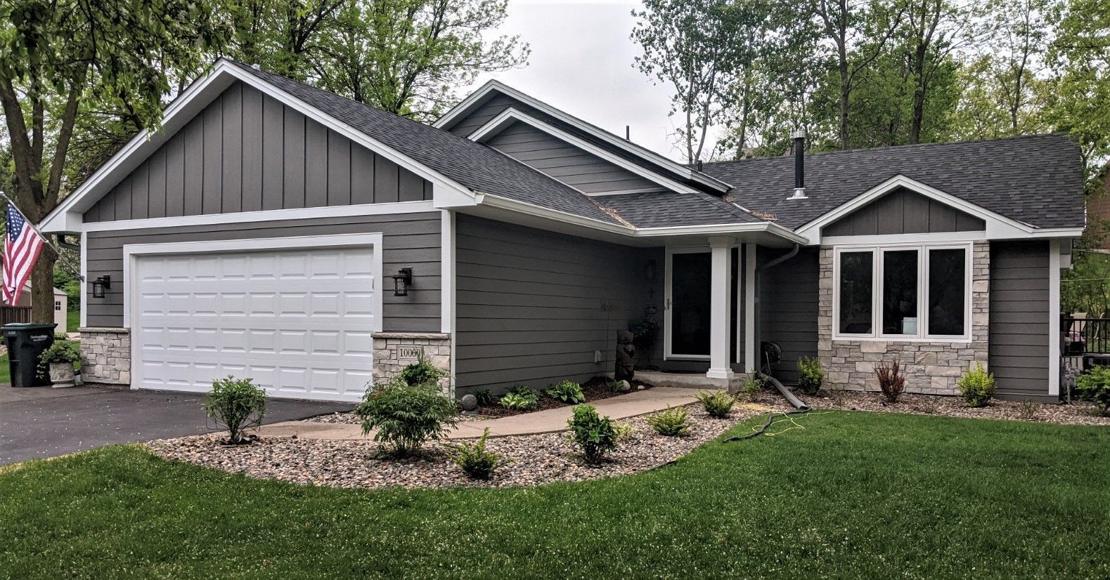 A large house with a large garage and an american flag in front of it.