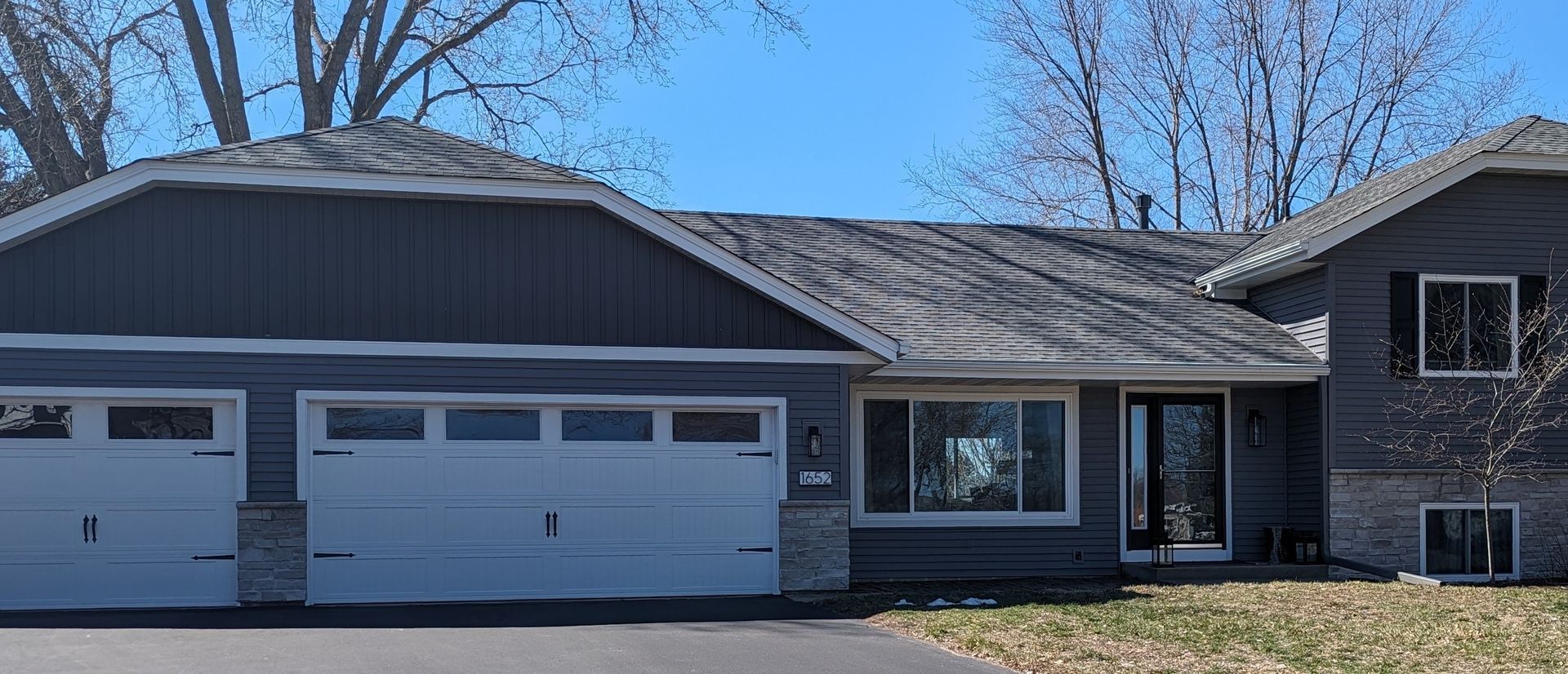 A house with two garage doors and a blue sky in the background.