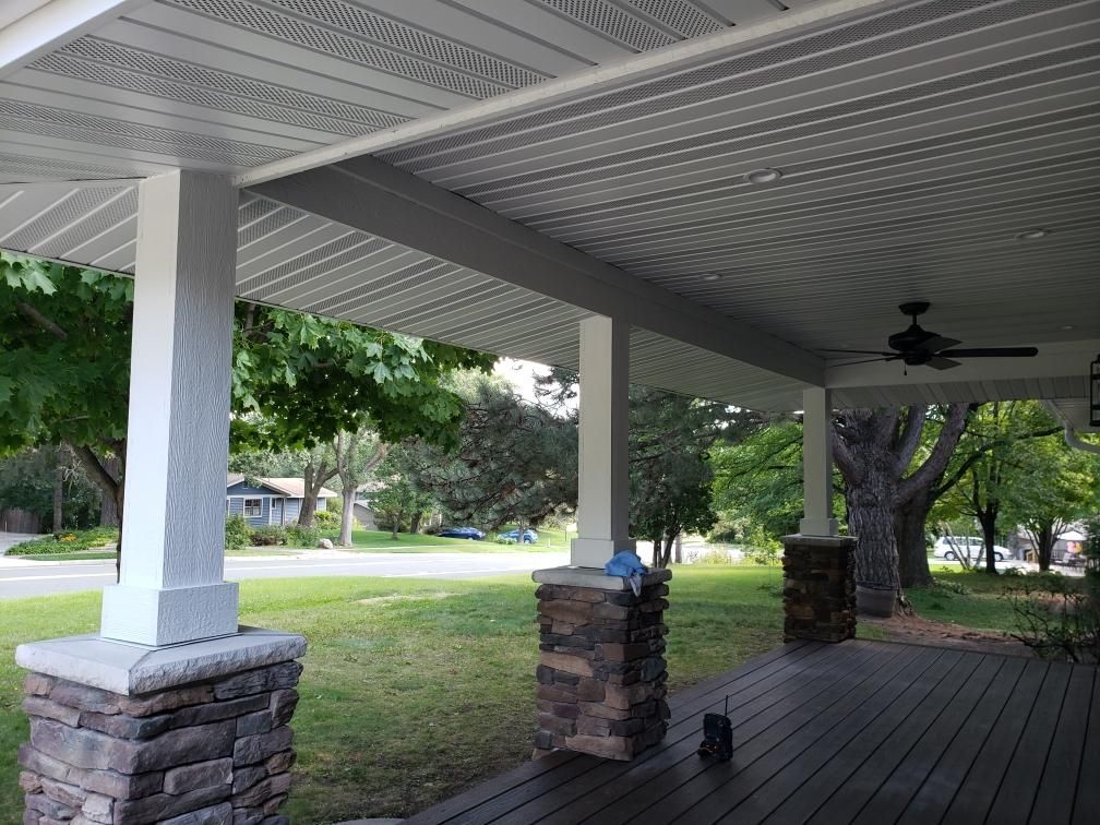 A porch with a ceiling fan and stone pillars