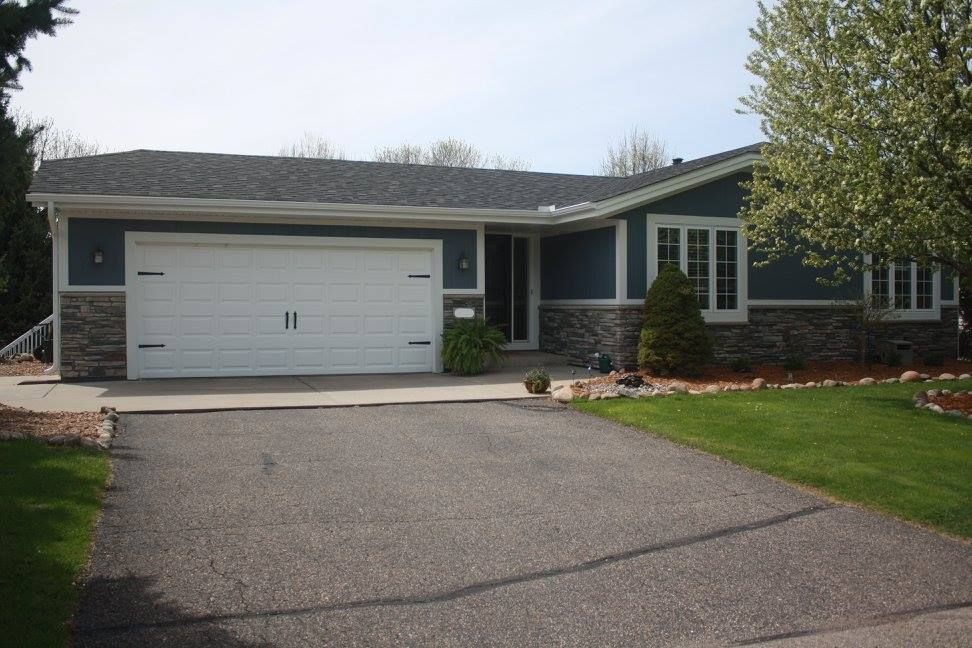 A blue house with a white garage door and a driveway