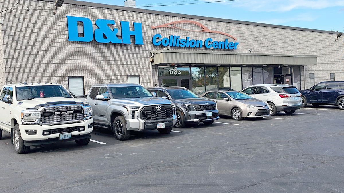 A group of cars are parked in front of D and H Collision Center building