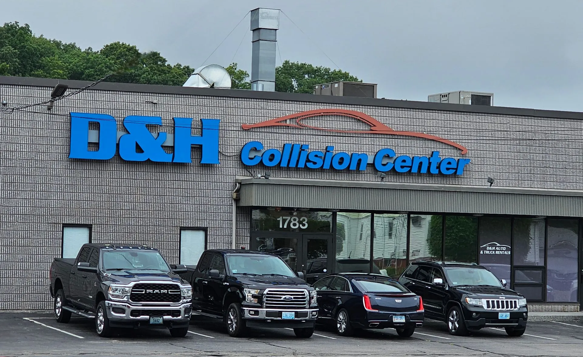 A row of cars are parked in front of a building that says d & h collision center.