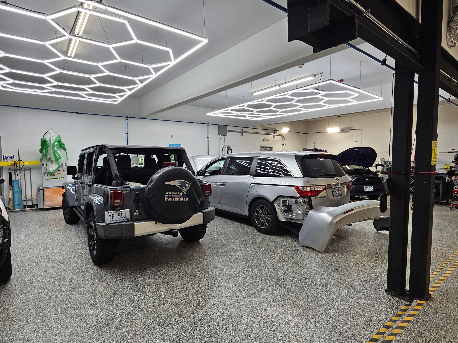 A jeep and a car are parked in a garage.