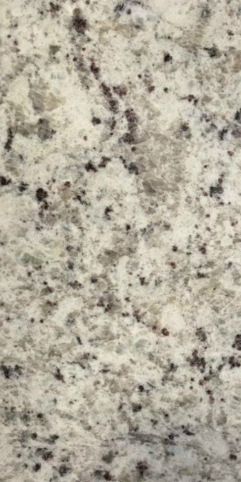 A close up of a white granite counter top with black spots.