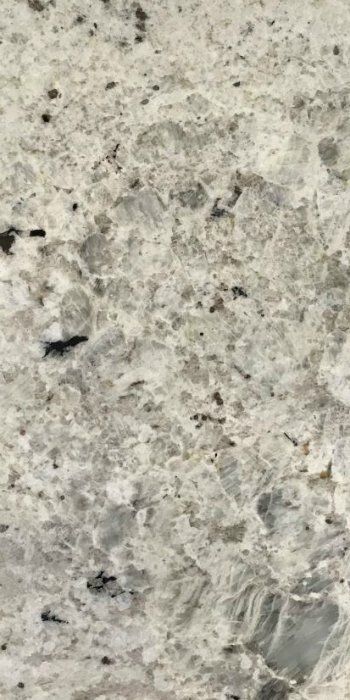 A close up of a white granite counter top with black spots.