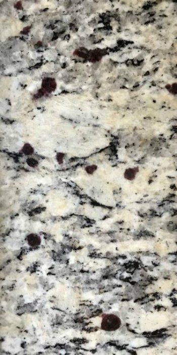 A close up of a granite counter top with red spots on it.