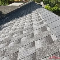 A close-up view of a new gray asphalt shingle roof showing the overlapping pattern and texture.