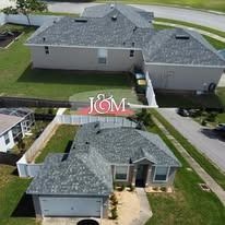An aerial view of two residential homes featuring newly installed shingle roofs, with a J&M company logo overlay.