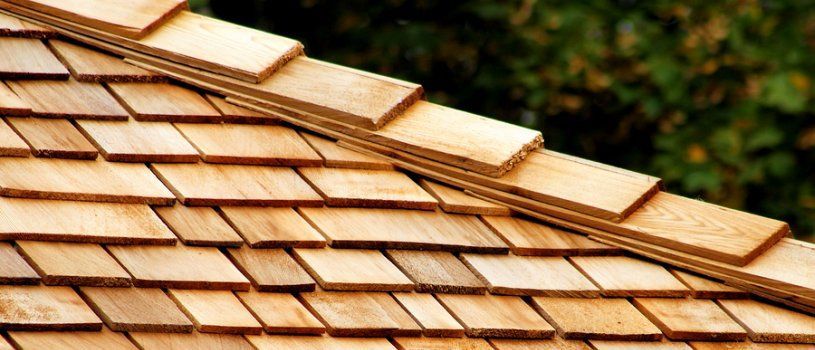 A close-up view of a roof covered in overlapping cedar wood shingles with a ridge cap running along the peak.