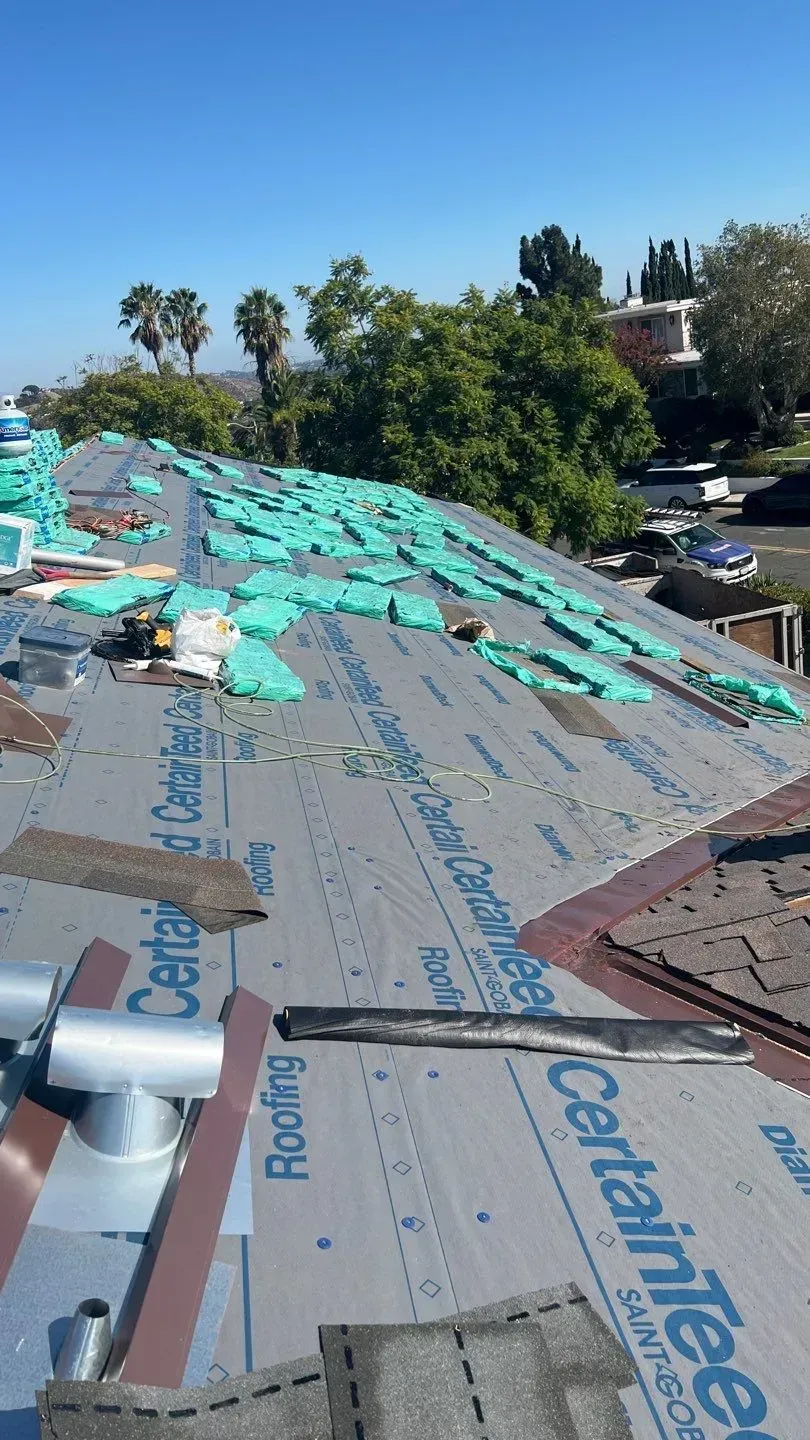 Roof with insulation, tar paper, and vents under construction on a sunny day.