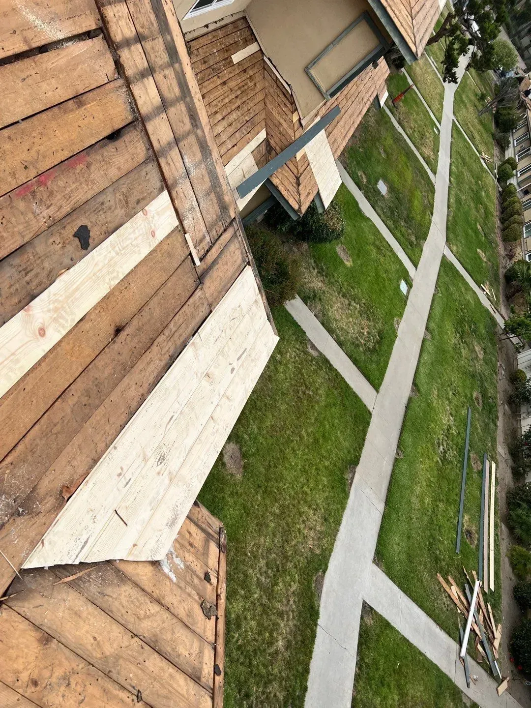 View from roof showing construction; boards, grass, walkways, and buildings.