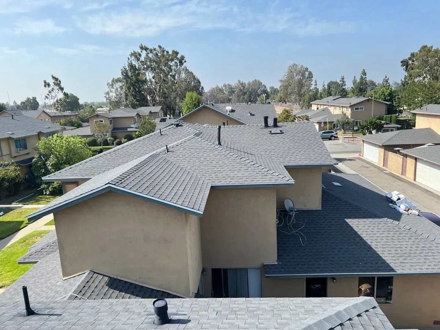 Overhead view of tan apartment buildings with gray roofs, on a sunny day.