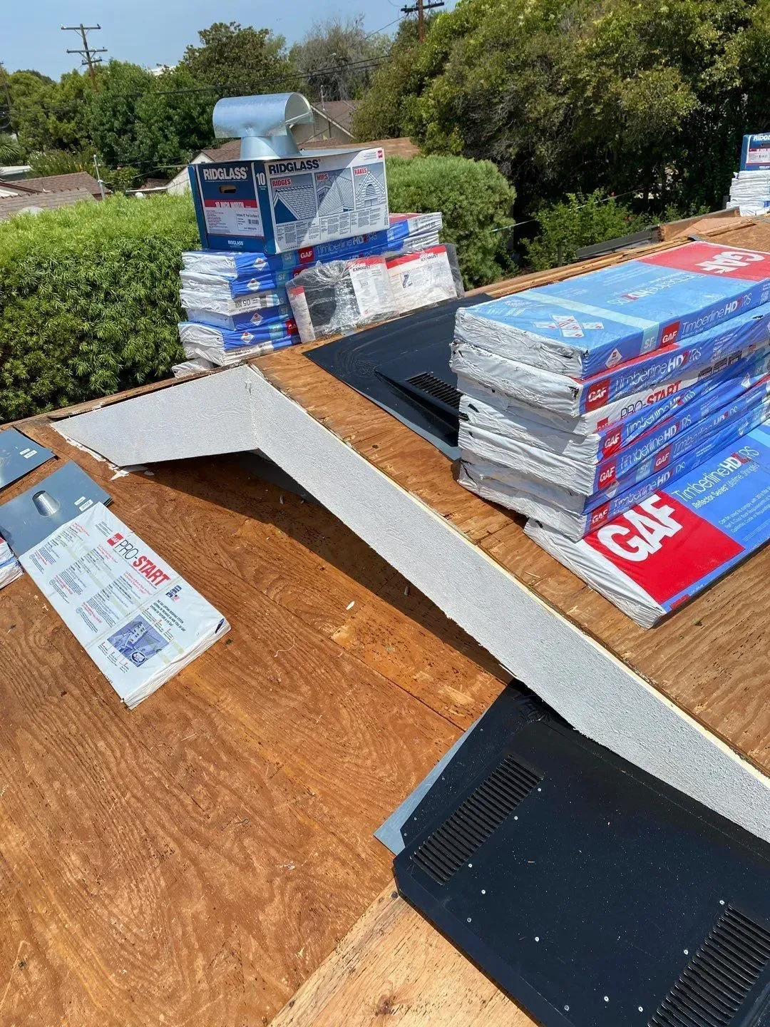 Rooftop with roofing materials, including boxes of shingles and flashing, ready for installation.