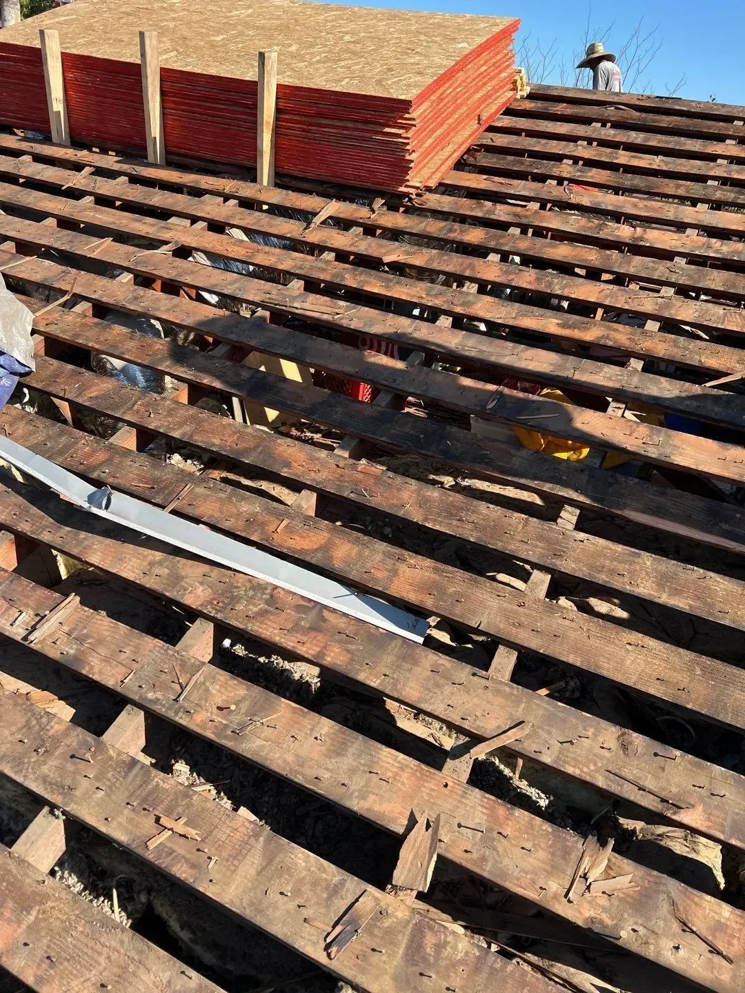 Roof under construction, showing wooden supports, stacked tiles, and tools.