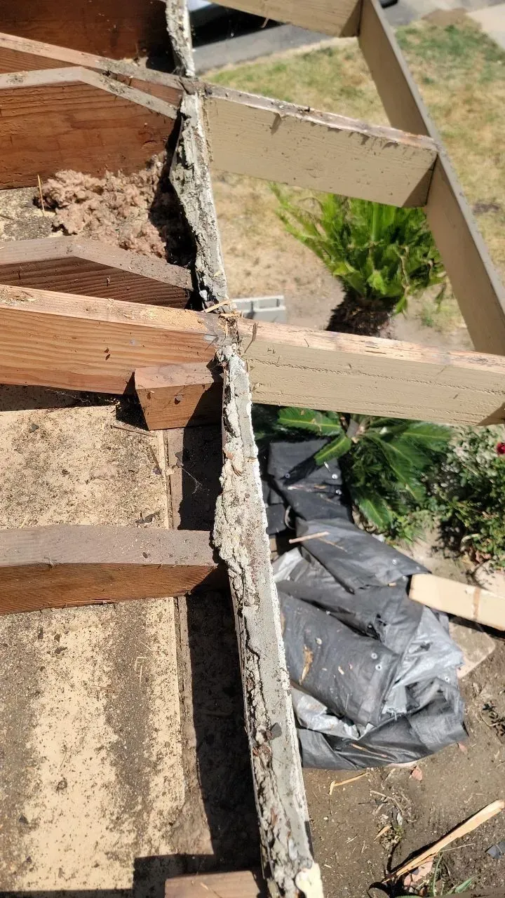Decayed wooden structure, possibly a deck, with visible damage and debris.