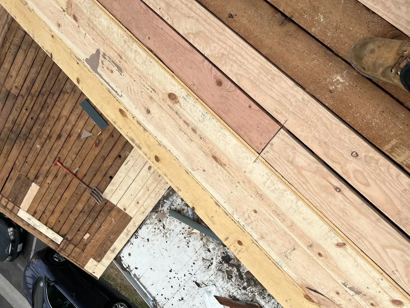 Overhead view of wood planks, some light colored, some weathered, possibly a deck being built.