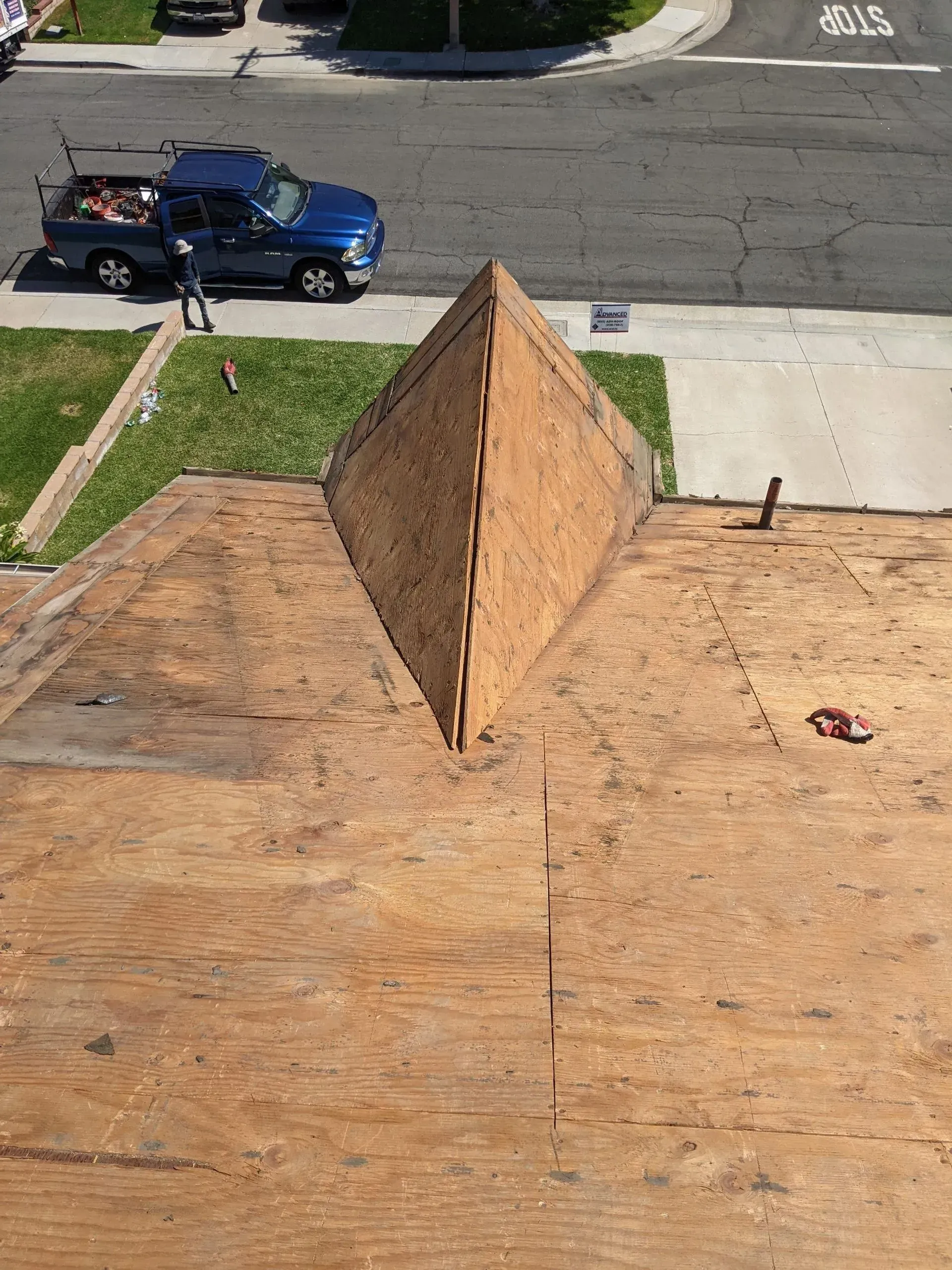 View of a brown, unfinished roof with a truck parked in the street.