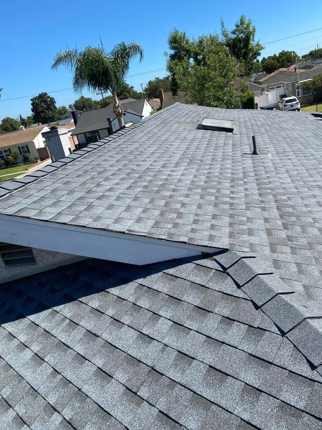 Gray asphalt shingle roof on a residential home under a blue sky.