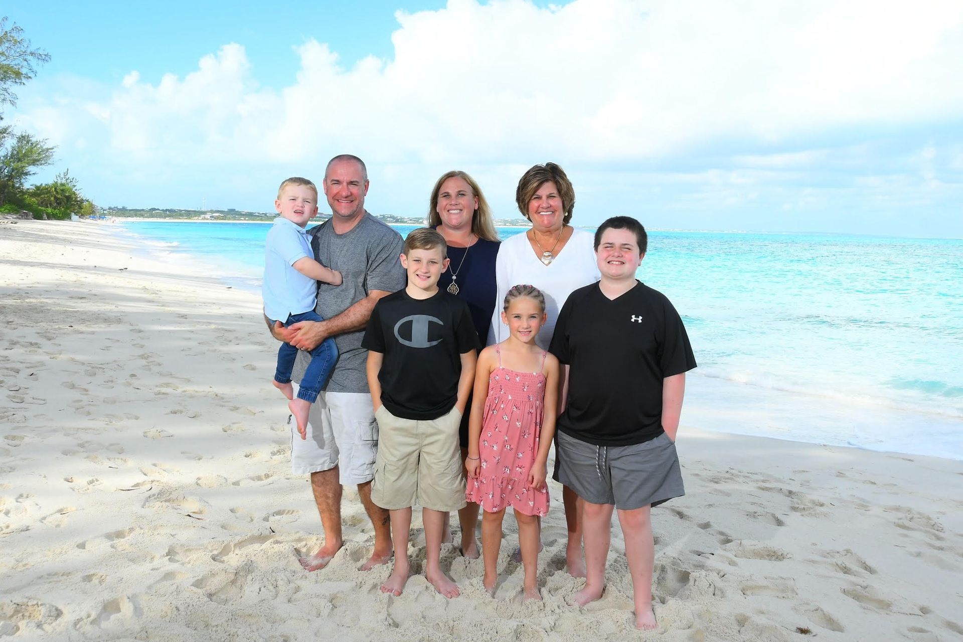 A family is posing for a picture on the beach.