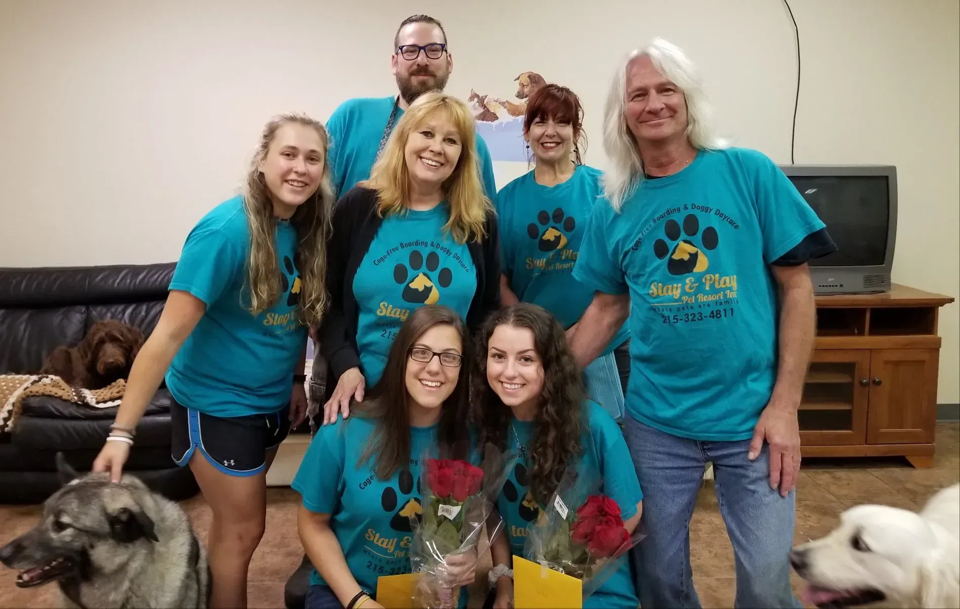 A group of people wearing blue shirts with paw prints on them are posing for a picture.