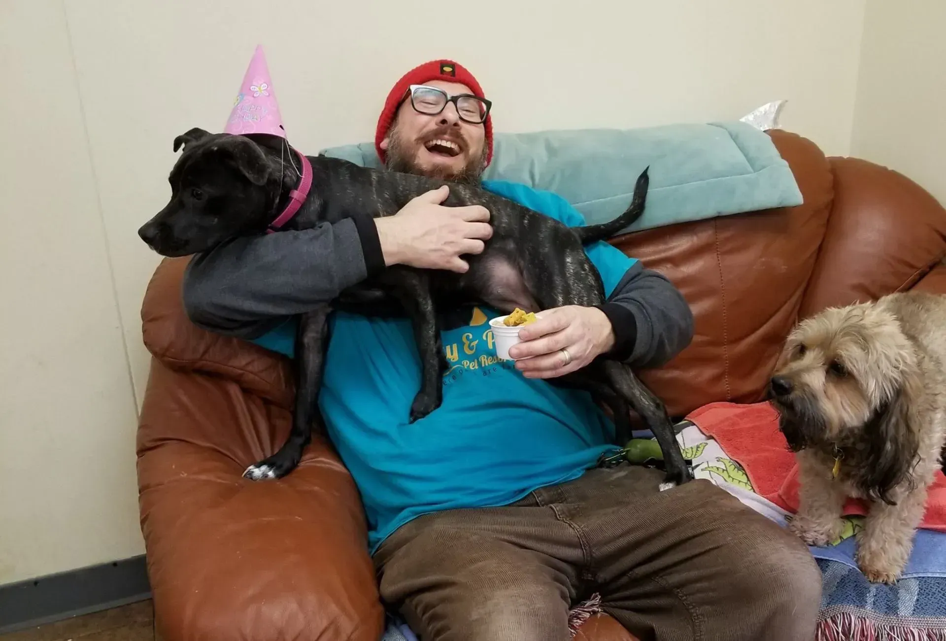 A man is sitting on a couch with two dogs.