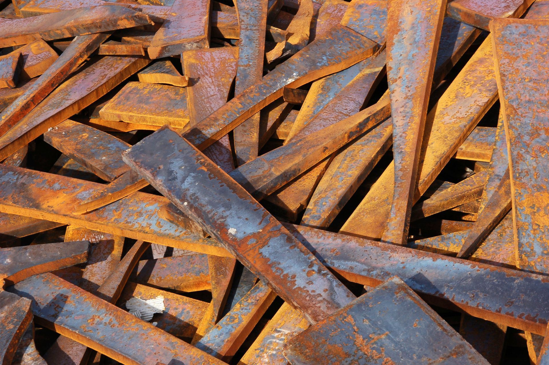 Rusty metal scraps and twisted beams stacked in a pile, with orange-brown corrosion throughout