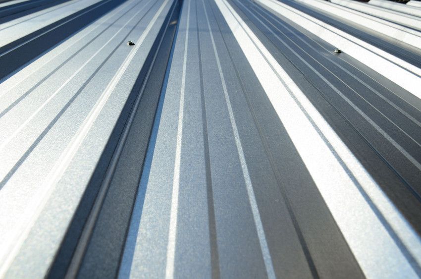 Diagonal view of a gray metal roof with white and blue reflective panels