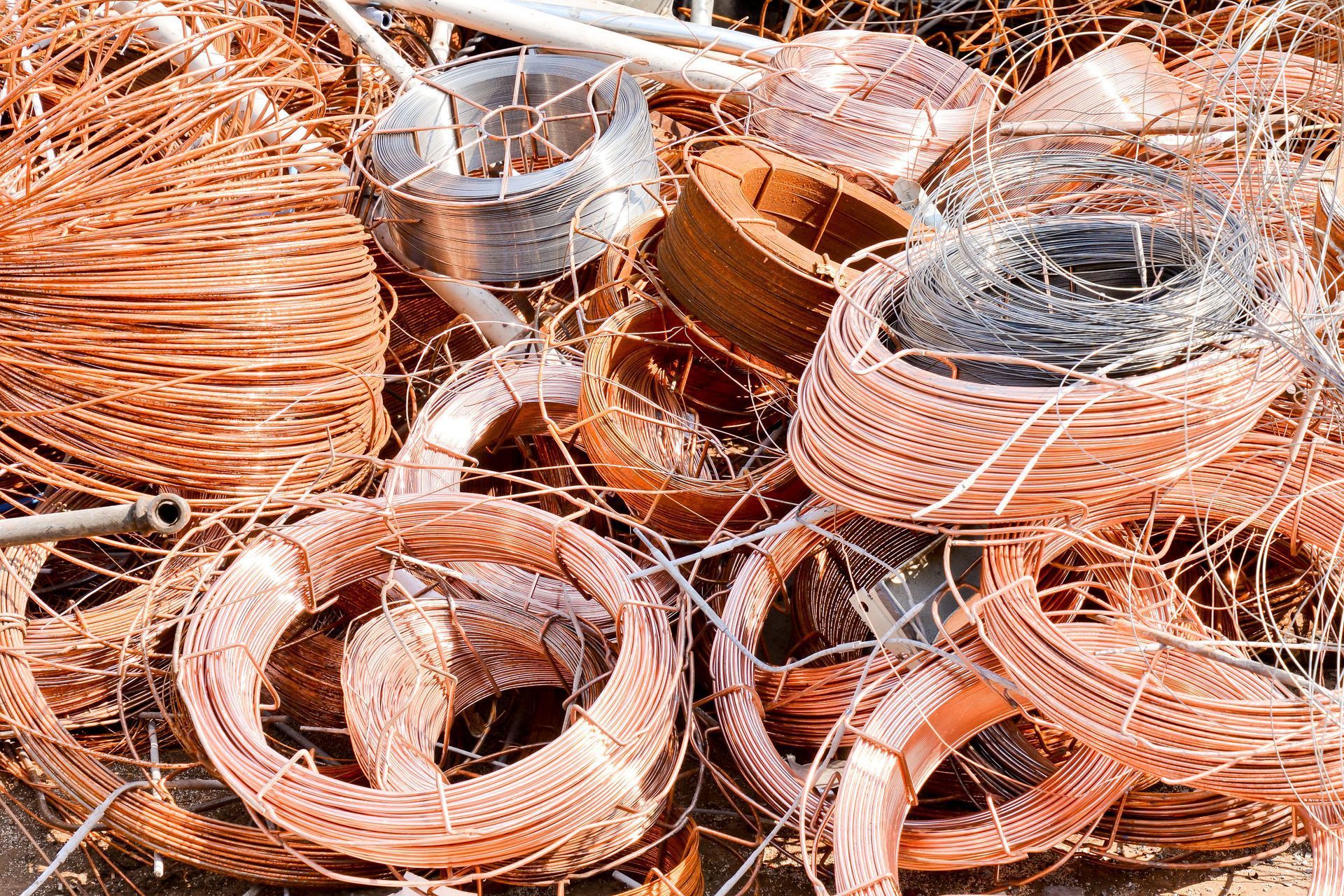 Coils of copper wire and scrap metal piled together in a scrapyard