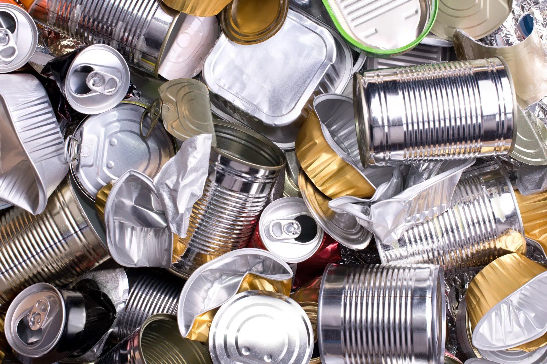 Assorted crushed aluminum cans piled together in silver and gold tones.