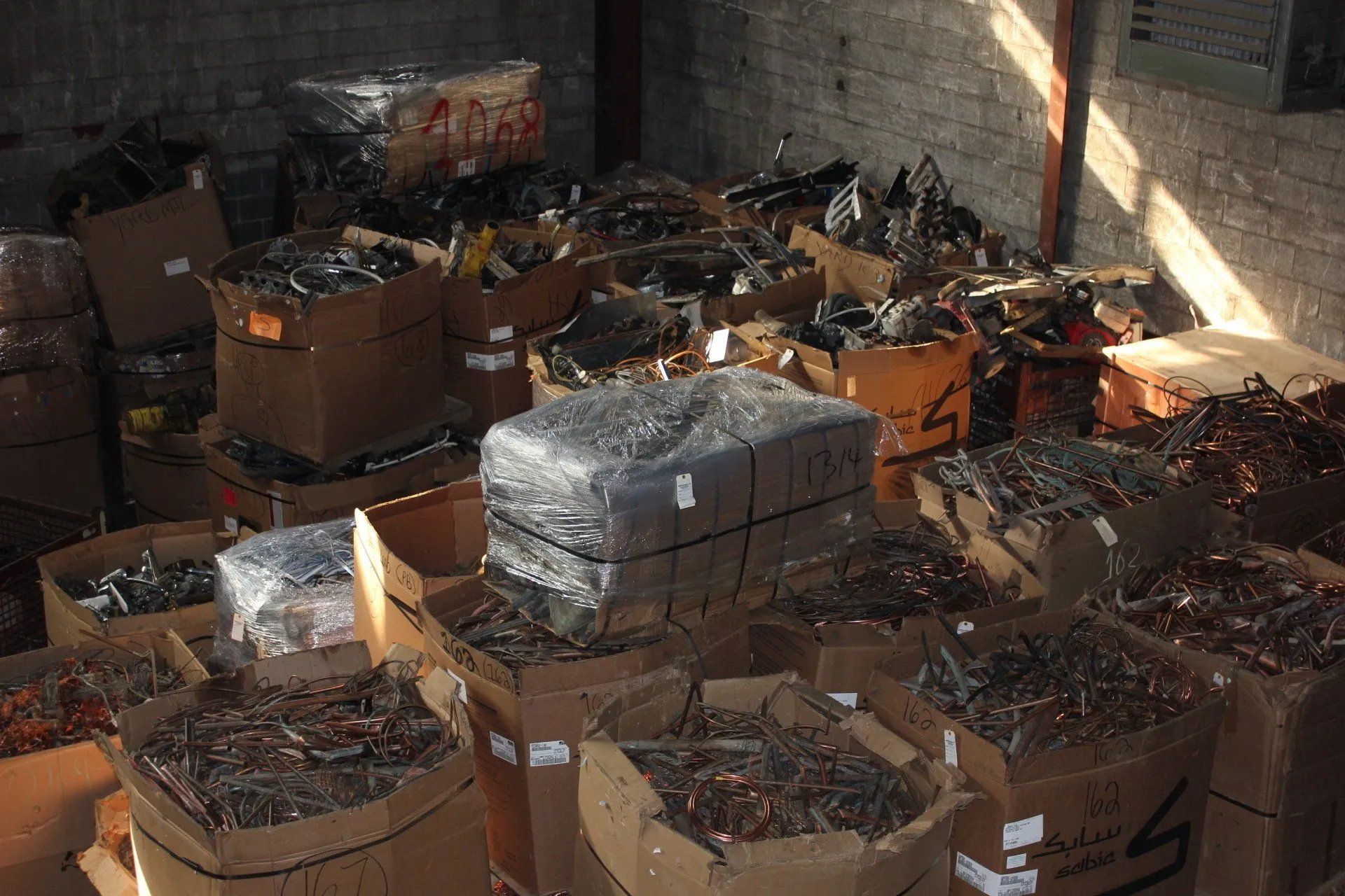 Boxes filled with scrap metal stacked in a dim warehouse or storage area