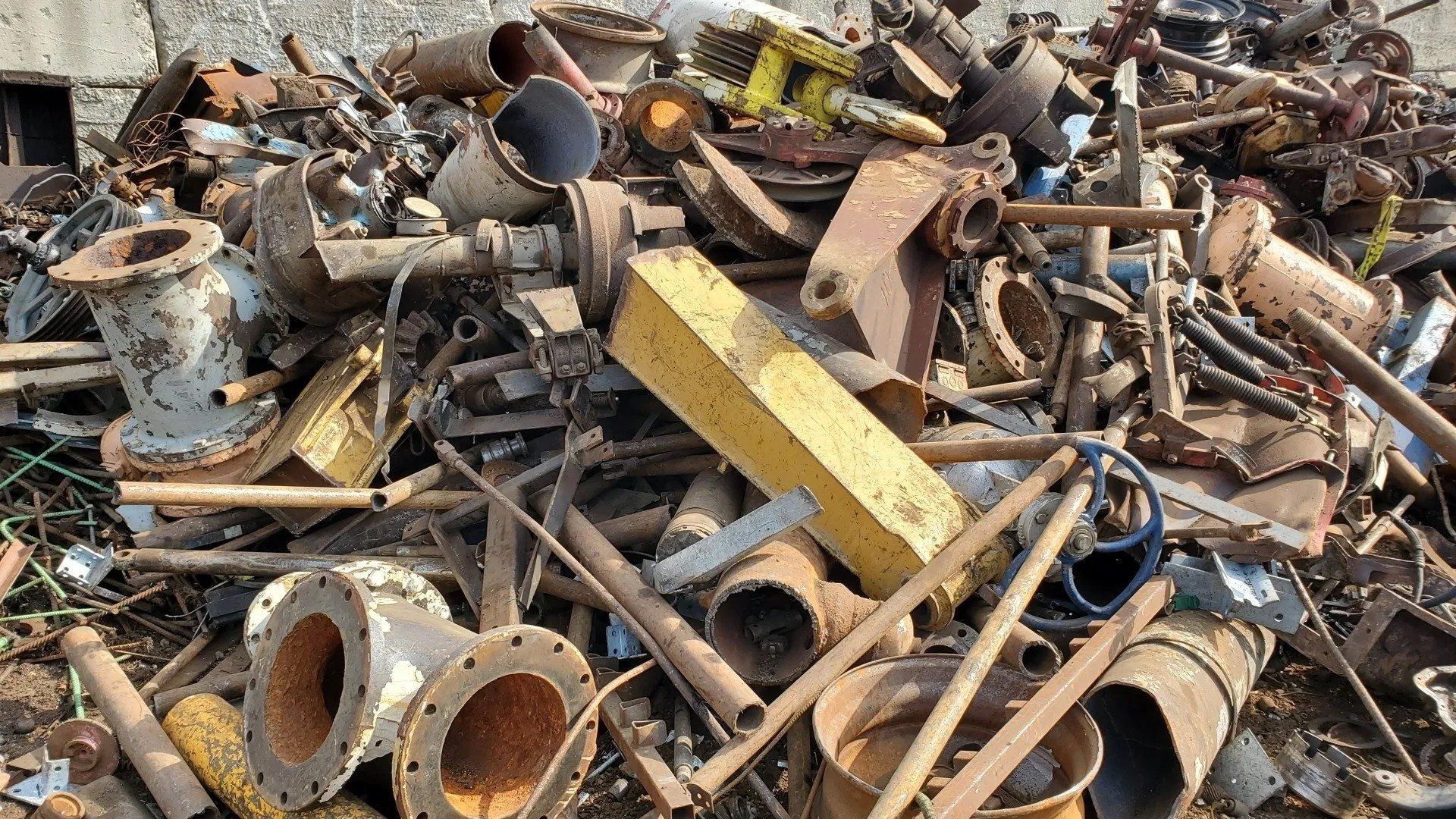 Pile of rusted scrap metal and pipes in an outdoor junkyard