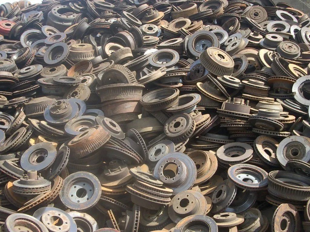 Pile of stacked metal gears and circular parts in a scrapyard or industrial storage area